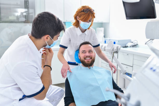 paziente maschio sorridente felice di farsi curare i denti da dentisti professionisti - dentist dentist office patient discussion foto e immagini stock
