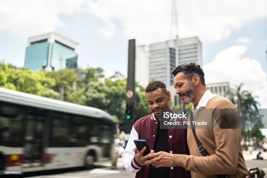 Gay couple using the mobile phone in the street Friendship Stock Photo