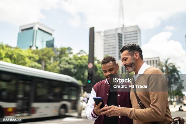 Gay Couple Using The Mobile Phone In The Street Stock Photo - Download Image Now - Friendship, Telephone, Two People