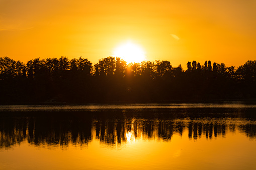 Landscape on the lake at sunset time, silhouette of trees