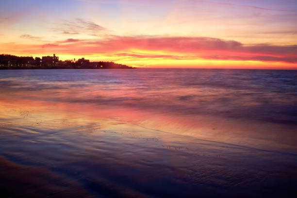 Scenario in Mazatlan Sinaloa, sunset with red and purple colors, sea reflecting the colors of the sky with a city on the peninsula