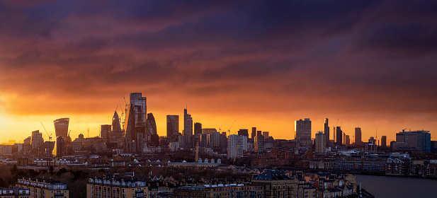 Wide panorama of the urban London City skyline during a fiery sunset, England