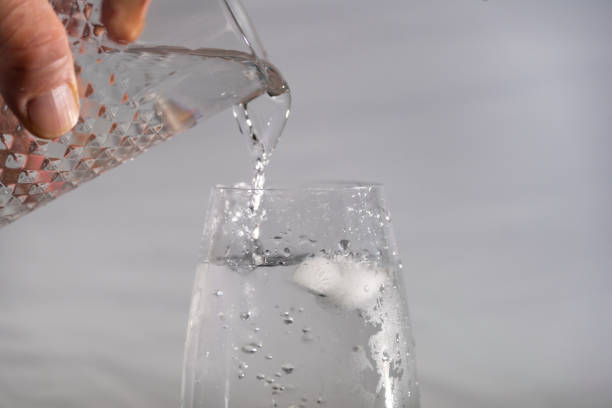istock Glass with running clean water and gray background 1385193079