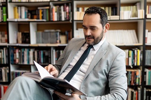 Young businessman in library ,bookstore holding book reading