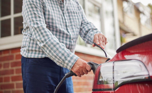 istock Close Up Of Man Attaching Charging Cable To Environmentally Friendly Zero Emission Electric Car At Home 1385197957