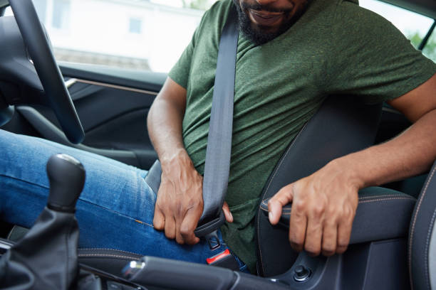 gros plan d’un conducteur masculin dans une voiture attachant sa ceinture de sécurité avant de partir en voyage - buckle photos et images de collection