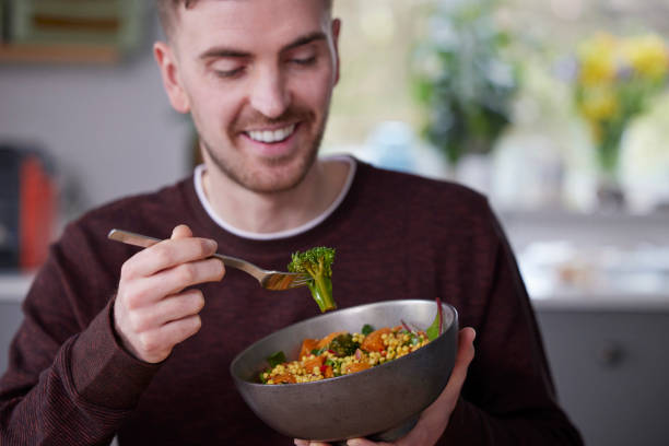 primer plano del hombre comiendo un almuerzo vegano saludable en la cocina en casa - raw potato red potato red vegetable fotografías e imágenes de stock