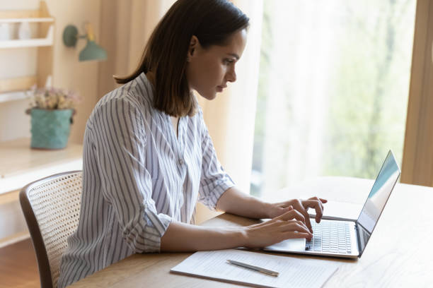 istock Serious businesswoman sit at table types texting on laptop keyboard 1385199030