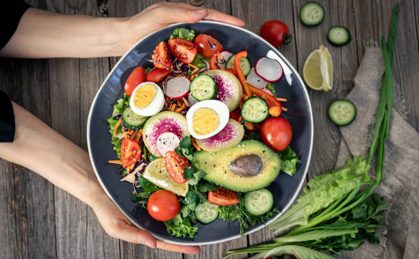 istock Appetizing vegetable salad with eggs, avocado on a wooden background. 1385201985