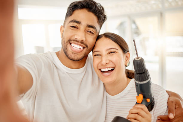 tiro de um jovem casal parado juntos e tirando uma selfie enquanto seguravam equipamentos de manutenção em casa - home improvement drill house repairing - fotografias e filmes do acervo