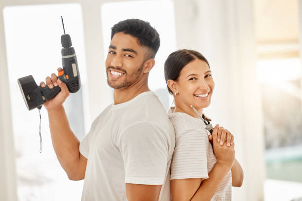 снимок молодой пары, стоящей спиной к спине в доме и держащей в руках оборудование для технического обслуживания - holding screwdriver стоковые фото и изображения