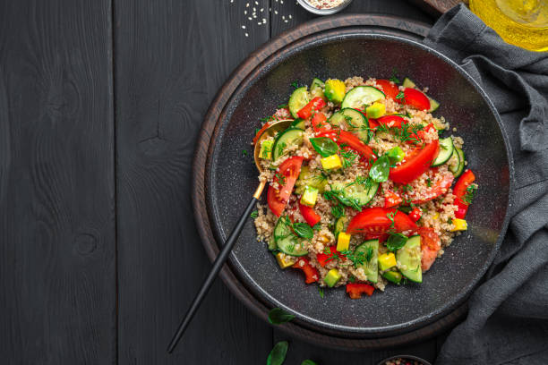 istock Healthy salad with quinoa, vegetables and fresh herbs on a black background 1385205508