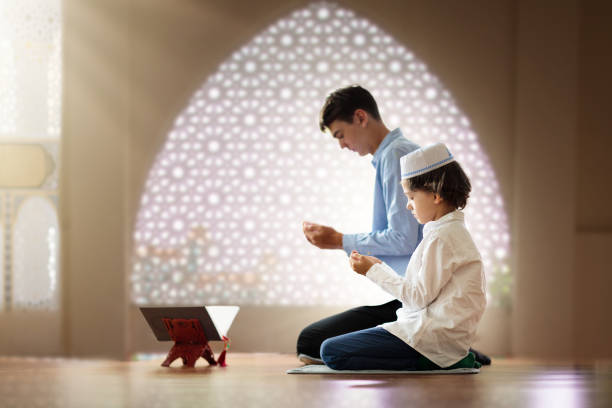 Ramadan Kareem greeting. Father and son in mosque. Ramadan Kareem greeting. Father and son in mosque. Muslim family praying. Man and child read Quran and pray. End of fasting. Hari Raya day. Eid al-Fitr celebration. Breaking of holy fast day. father allah stock pictures, royalty-free photos & images