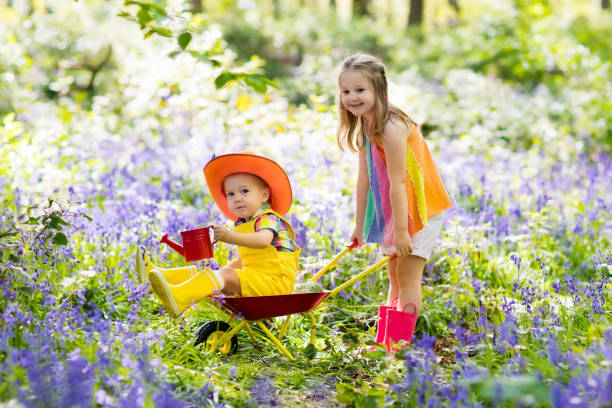 istock Kids with bluebell flowers, garden tools 1385207460