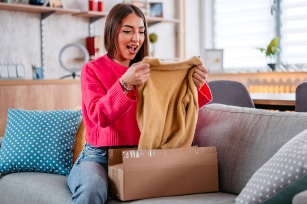 istock Young Woman Unpacking A Package With A New Sweater 1385207941