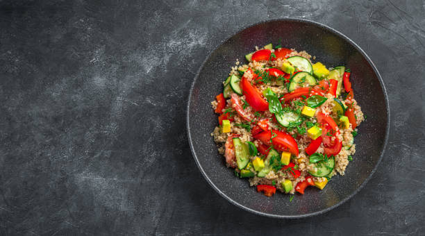 istock Fresh vegetable salad with avocado, tomatoes, cucumber and quinoa on a dark background 1385209028