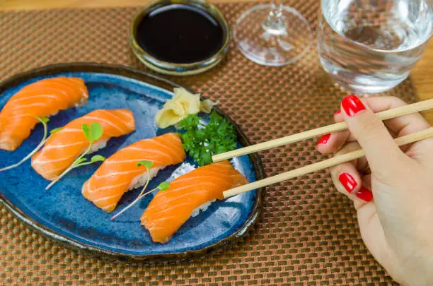 Delicious premium salmon nigiri on blue handmade plate decorated