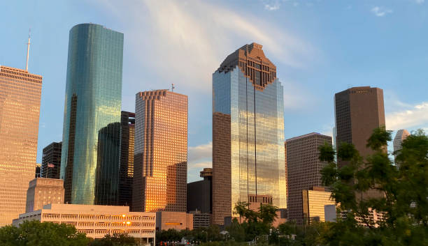 primer plano del horizonte de houston y el ayuntamiento con bandera ondulante en la hora dorada - houston texas skyline texas office building fotografías e imágenes de stock