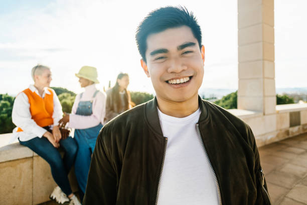 istock Young confident asian man smiling at camera while standing with friends outdoors 1385226428