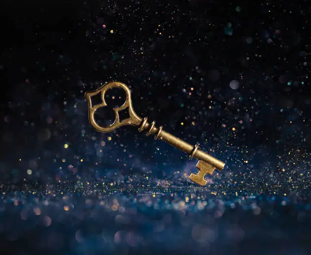 Photo of Single golden skeleton key surrounded by sparkling lights. Business concepts of unlocking potential, key to success, or financial opportunity.