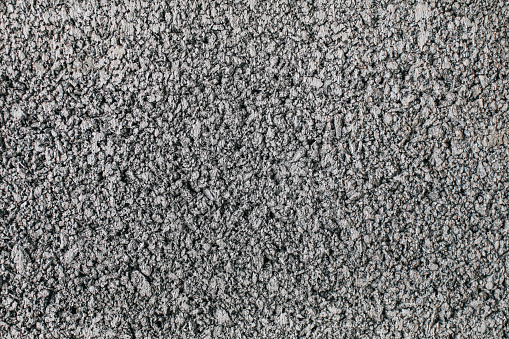 ฺBackground texture of rough asphalt floor. Close-up horizontal grey granite gravel floor.