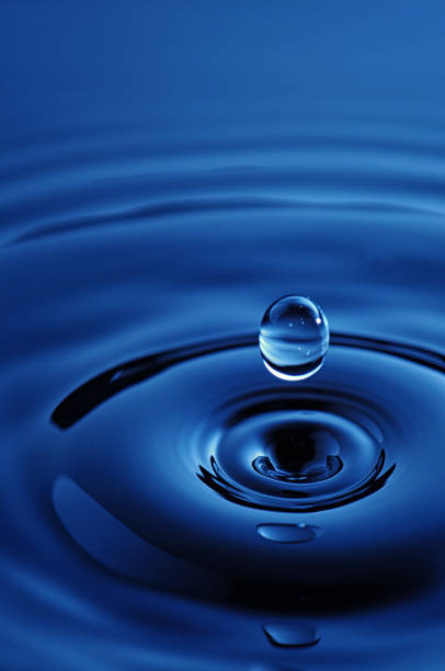 Drop of Water Falling Into a Rippled Blue Pool stock photo