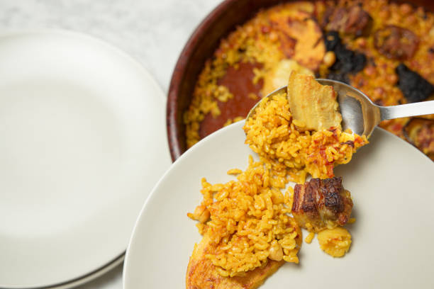 istock Man's hands serving oven-baked rice on a plate with a spoon. Valencia, Spain 1385249483