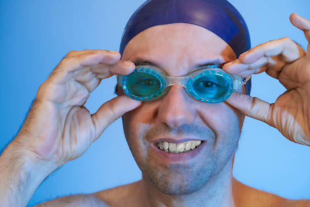 Man putting on his goggles to start swimming