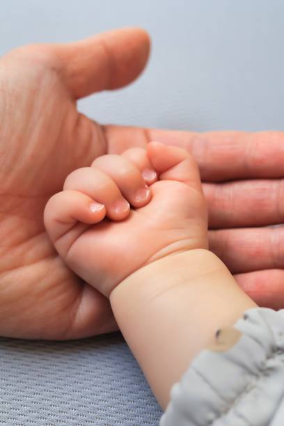 istock A big hand that wraps the baby's cute hand 1385282698