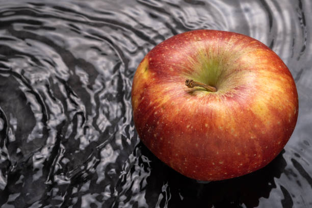 close-up of red apple in water with waves and copy space