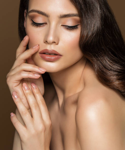 beauty model face make up with beige lipstick and perfect eyeliner. woman skin and lips care cosmetics. women hands with nude nail polish over brown background - women beauty beautiful fashion model imagens e fotografias de stock