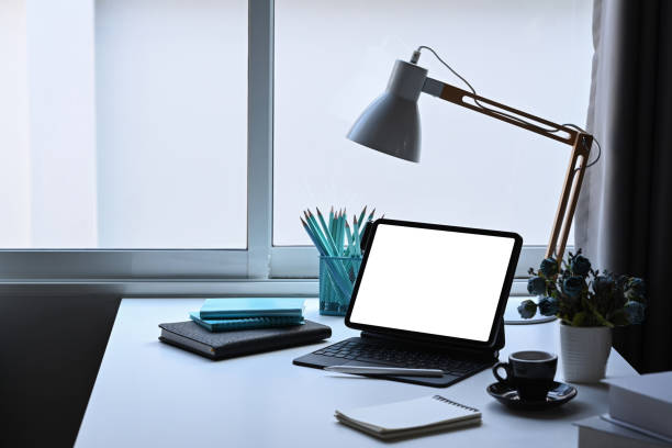 istock Home office desk with computer tablet, lamp, flower pot and stationery. 1385314578