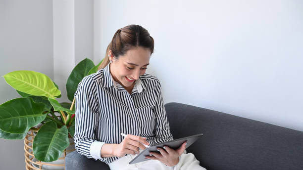 istock Relaxed millennial woman sitting on couch and using digital tablet. 1385314936