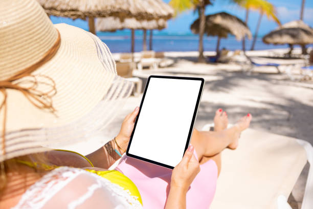 istock Woman on tropical beach holding tablet in vertical screen orientation 1385322488