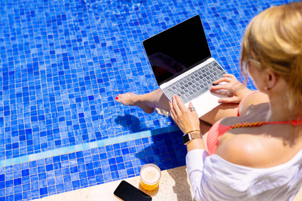 istock Woman working on laptop computer by the pool 1385323043