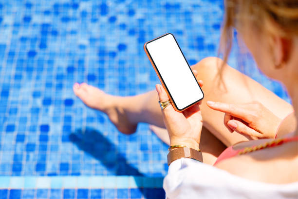 istock Woman using mobile phone by the pool 1385323111