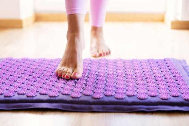 istock Woman using acupressure mat for feet massage therapy 1385323166