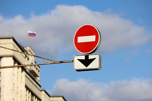 Stop sign on background of State Duma of Russia and Russian flag against blue sky