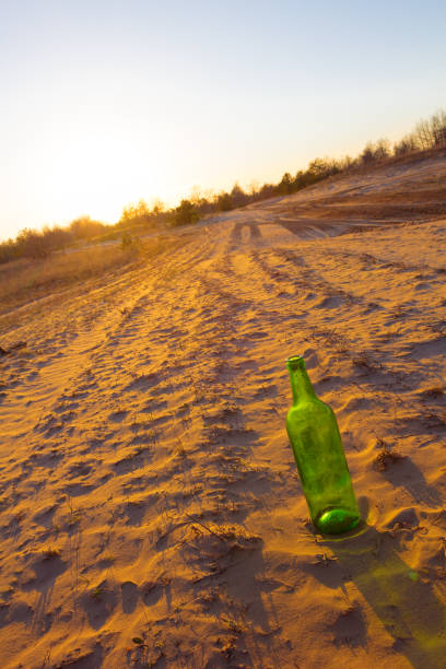 istock bottle on a sand at the evening 1385333255
