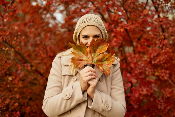 istock Young smiling woman holding autumn leaf in hands 1385339599