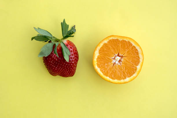 istock Fresh strawberry and orange half on yellow background 1385340911