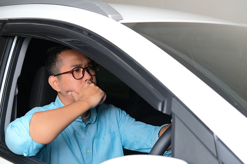 Adult Asian man driving his car with serious face expression