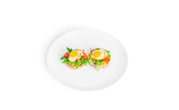istock Crispbread sandwich with guacamole, arugula, tomatoes and quail egg isolated on a white background. Bruschetta with avocado. Healthy breakfast 1385345753