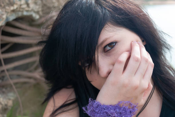 Emo punk gothic girl looking at camera, close-up Emo punk woman smiling, looking at camera while holind her head in her right hand, horizontal black hair emo girl stock pictures, royalty-free photos & images