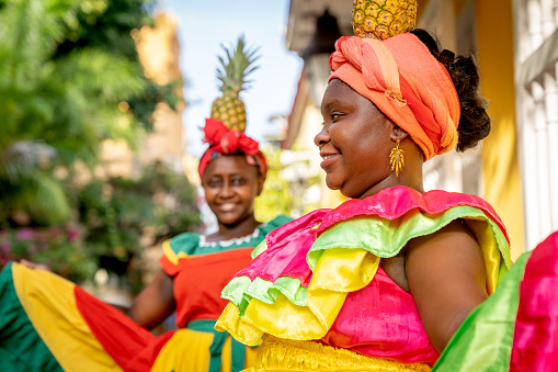 Cartagena Colombia 19 May 2021 : Two palenqueras with pineapple are posing showing their multicolor traditional dress at the old town of Cartagena de Indias.
