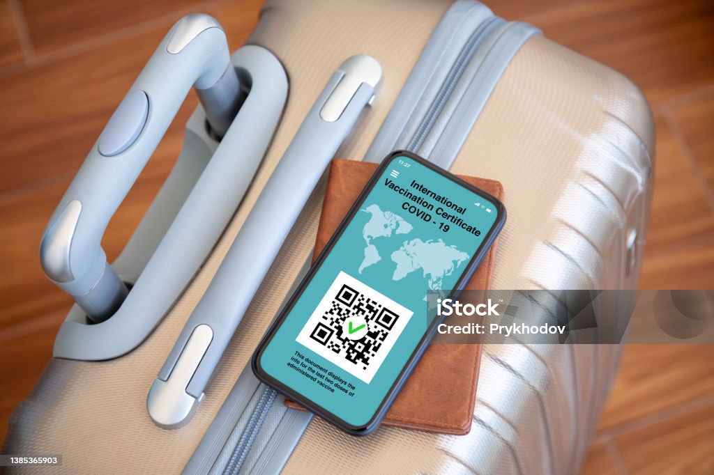 phone with international vaccination certificate covid 19 background suitcase phone with international vaccination certificate covid 19 on screen background suitcase at airport QR Code Stock Photo