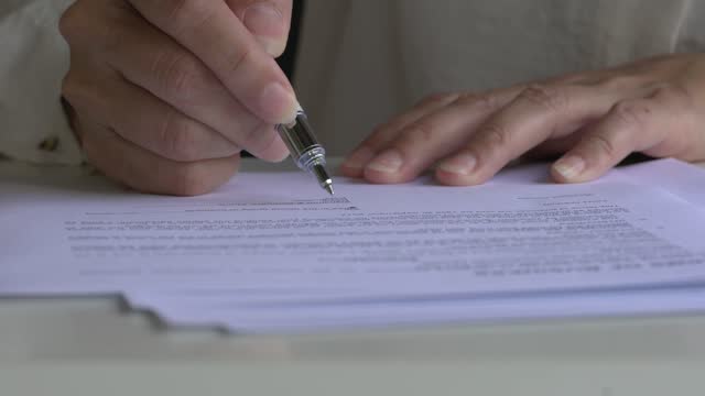 Close up view of businesswoman signing contract document.