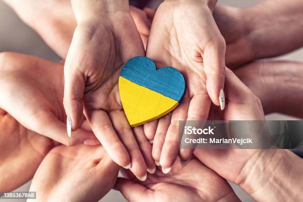 We Stand With Ukraine Symbol As Numerous Hands Hold One Another In Unity With A Wooden Heart Painted In Ukrainian Flag Colors On Top Stock Photo - Download Image Now