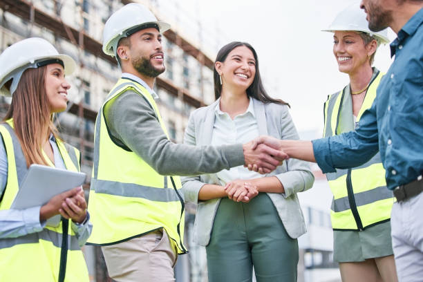 shot of a team of builders shaking hands on a construction site outside - building contractor fotos imagens e fotografias de stock