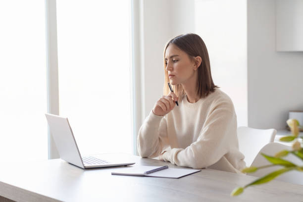 istock A young beautiful woman working on a laptop, sitting in the kitchen at home, remote work, freelance. 1385369675